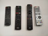 quatre télécommandes sont alignées sur une surface blanche