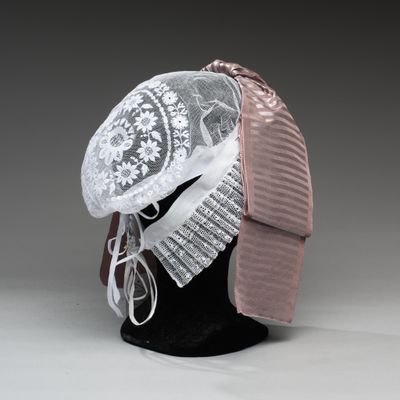 un chapeau blanc orné d'un ruban rose posé sur la tête d'un mannequin