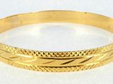 a close up of a gold bracelet on a white surface