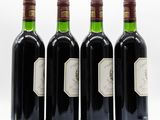 four bottles of wine are lined up on a white surface