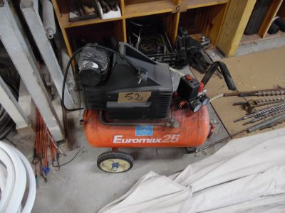 un petit compresseur d'air posé dans un garage avec d'autres outils