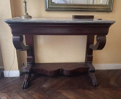 une table avec un plateau en marbre et un miroir accroché au mur