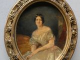 une vieille photo d'une femme en robe blanche, assise, dans un cadre doré