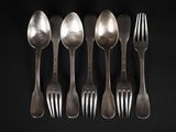 six spoons and a fork are lined up against a black background