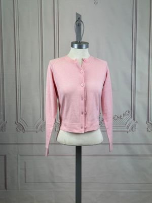 the pink cardigan sweater is on a mannequin base