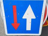 a blue and white sign with a red arrow on it