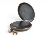 a small black pocket watch with a chain around it