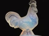the figurine is made of frosted glass and has a rooster on it ' s head