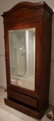 une armoire en bois avec une porte vitrée dans une salle de bains