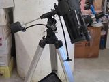 un télescope noir posé sur un trépied, à côté d'un livre