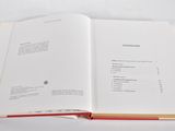 an open book on a white table with a red cover