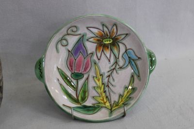 une assiette ornée d'un motif floral, posée à côté d'un vase