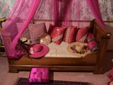un lit avec un baldaquin rose et des oreillers dessus