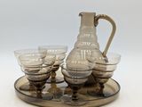 un pichet et six verres posés sur un plateau, avec un autre plateau en dessous