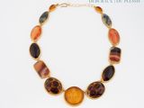 necklace with multi colored stones on a gold chain on a white background