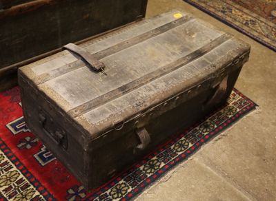une vieille malle posée sur un tapis, à même le sol