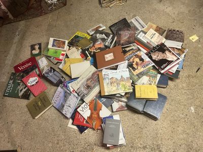 a pile of books on the floor next to a chair