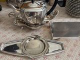 une théière en argent posée sur une table, à côté d'autres théières en argent