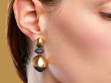 the woman is wearing a pair of gold and black earrings