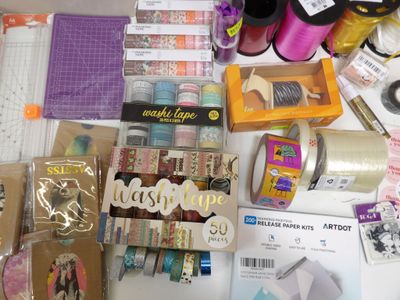 a table that has many items on it including scissors, tape, tape cutters, and other items