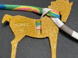 a gold horse that is tied to a colorful ribbon