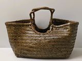 a small woven basket with a handle on a table
