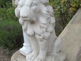 une statue représentant un lion assis sur un rebord