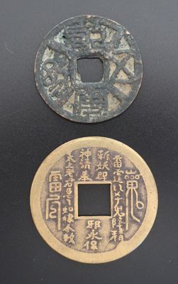 deux pièces chinoises posées l'une à côté de l'autre sur une surface noire