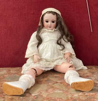 une poupée assise sur une table avec un fond rouge