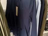three men ' s shirts hanging on a rack in a clothing store