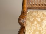 a close up of a wooden chair with a beige upholstered seat