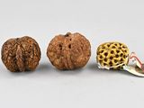 three walnuts and a nut shell on a white surface