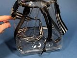 a person holding a clear bag with black and white handles