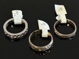 three silver rings with tags on them sitting on a black surface