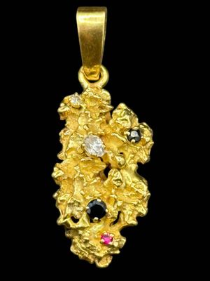 a close up of a gold pendant with a black and pink stone
