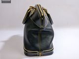 black leather handbag with gold zippers on a white surface