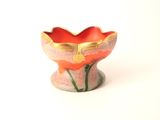 un petit vase posé sur une surface blanche