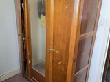 a wooden cabinet with a mirror in it in the corner of a room