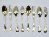 six silver spoons and six forks are lined up on a white surface