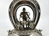une figurine en argent représentant un homme avec un chien dans un fer à cheval