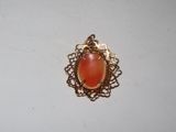 a close up of a gold pendant with a red stone in it