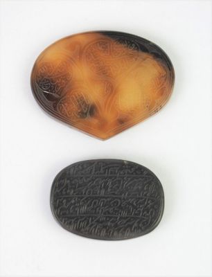 deux morceaux de tortoïde sculpté portant des inscriptions sur une surface blanche