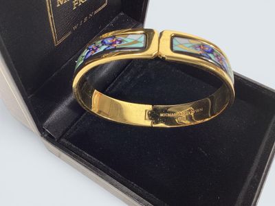 bracelet présenté dans un coffret noir, orné d'une bande dorée et d'un motif bleu et vert