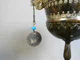 a silver vase with a blue bead hanging from it