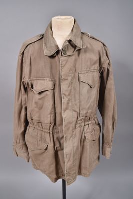 une veste marron posée sur un mannequin, devant un fond gris