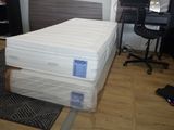 Des cartons contenant des matelas sont empilés les uns sur les autres dans une pièce