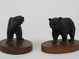 pair of black bear figurines on wooden bases on a white background