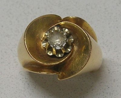 une bague en or sertie d'un diamant, posée sur une table