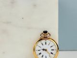 a small gold pocket watch sitting on a marble block