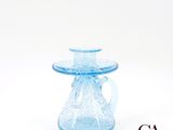 un vase en verre bleu muni d'une anse, sur fond blanc